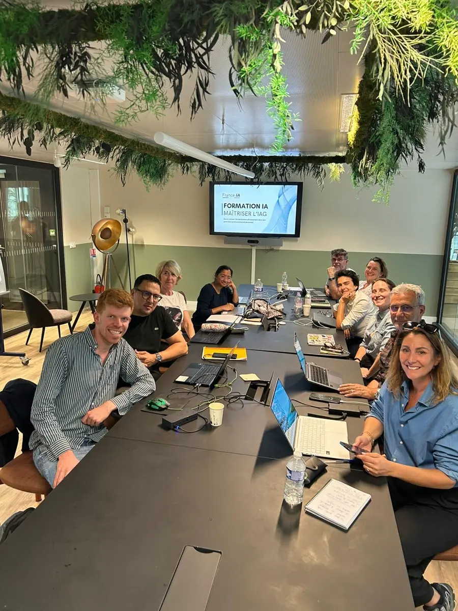 Groupe en session Formation IA autour de la table, écran de présentation au fond